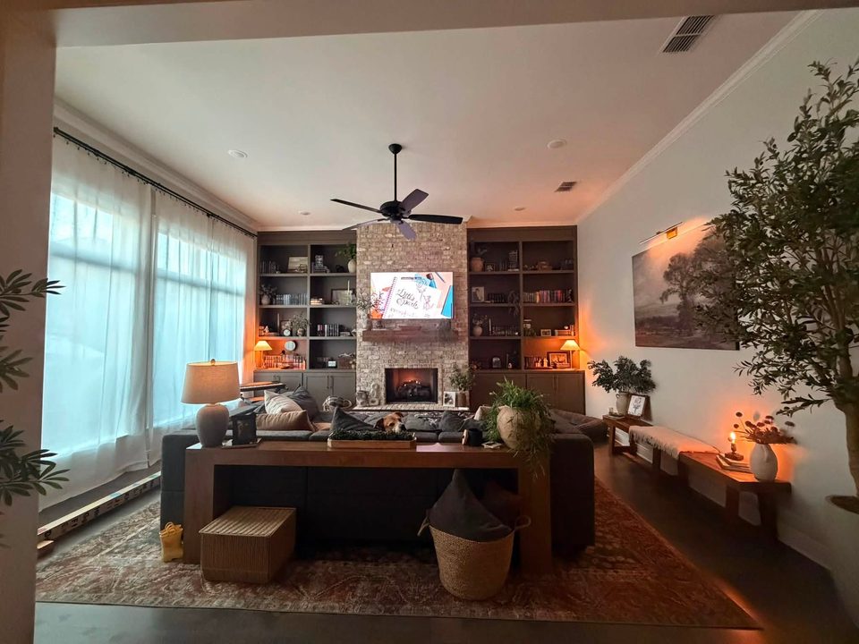 Wide view of living room with fireplace and built-in shelves.