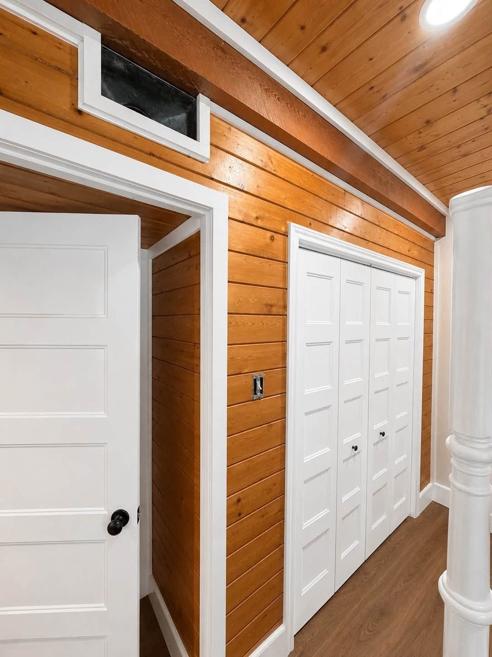 Wood-paneled interior with white door trim and ceiling beams.